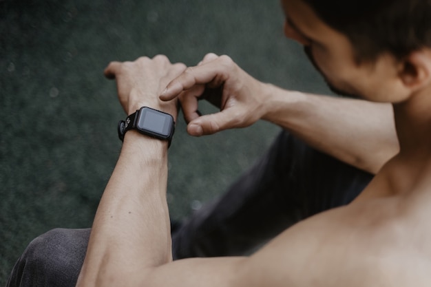 Mann, der smartwatch verwendet, während training ausruht