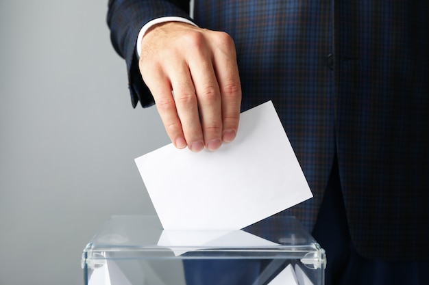 Mann, der Stimmzettel in Wahlurne setzt