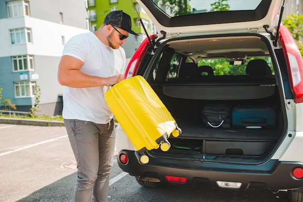 Mann, der Taschen in den Kofferraum legt, bereit für die Autofahrt