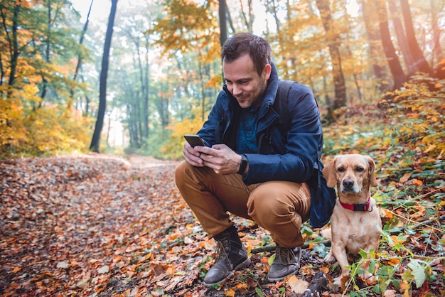 Mann, der Telefon im bunten Herbstwald verwendet