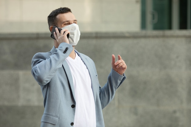 Mann, der Telefon in Gesichtsmaske auf der Straße benutzt