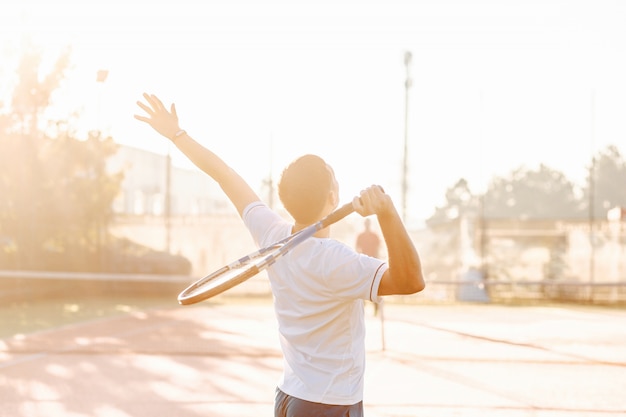 Mann, der Tennis am Morgen im Sonnenlicht spielt