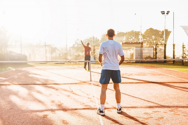Mann, der Tennis am Morgen im Sonnenlicht spielt