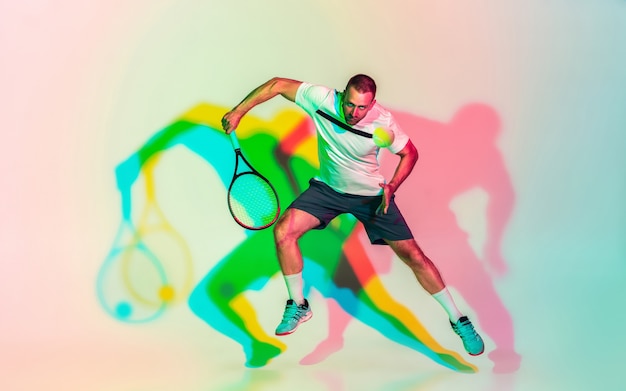 Mann, der Tennis spielt, isoliert im Studio in trendigem Neonlicht?