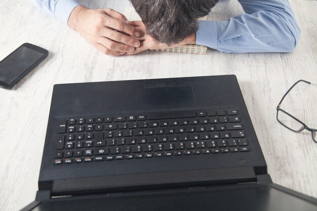 Mann, der über Arbeitsplatz im Büro schläft.