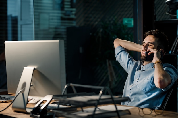 Mann, der über Telefon im dunklen Büro plaudert