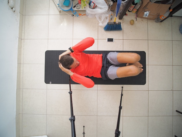 Foto mann, der übungen bauchmuskeln macht, die auf der gymnastikmatte liegen. ansicht von oben.