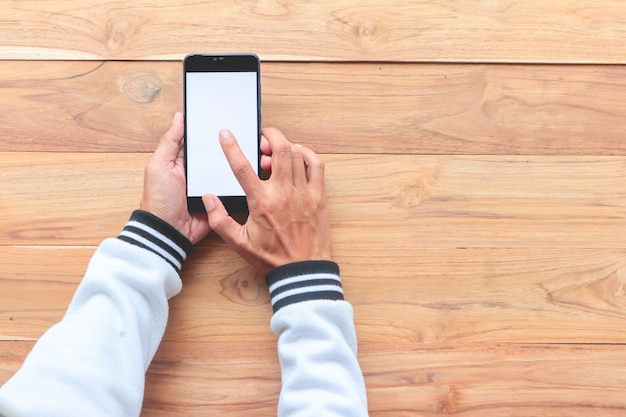 Mann, der weißen Schirm des Smartphones auf Holztisch verwendet.