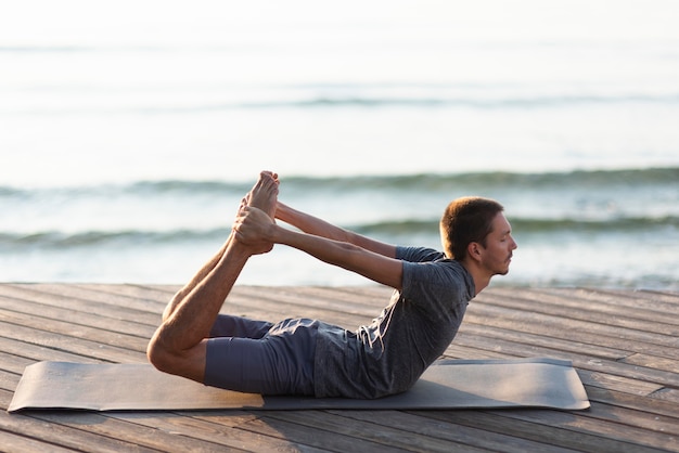 Mann, der Yoga nahe Meer tut