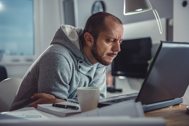 Mann, der zu Hause an Laptop arbeitet