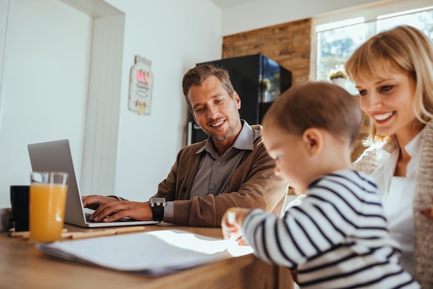 Mann, der zu Hause online arbeitet, während seine Frau und sein Sohn daneben zeichnen