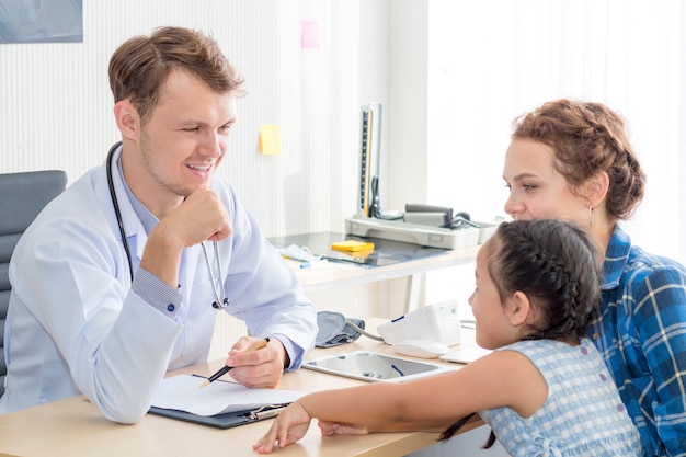 Mann des Kinderarztes (Doktor), der Fauststoß (hohe fünf zu) gibt, Kind an der Chirurgie beruhigt und bespricht. Bemuttern Sie den Kaukasier und Kind, die im Krankenhauszimmer lächeln