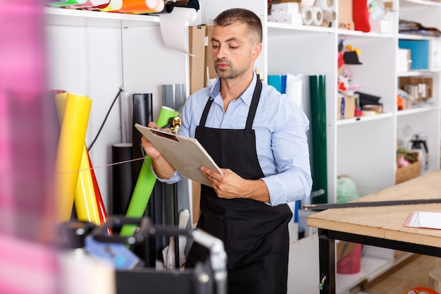 Mann-Designer und Druck-Operator mit Vinyl-Papier bei der Druckherstellung