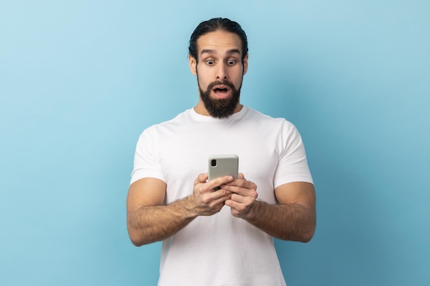 Mann drückt Schock aus, während er mit dem Handy erstaunliche Nachrichten im Internet durchsucht