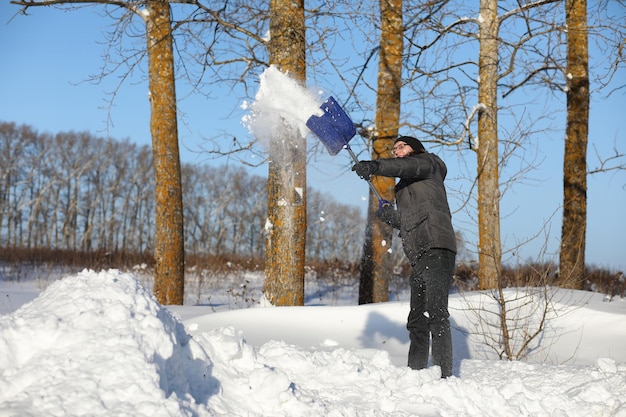 Mann entfernt Schnee mit Schaufel von der Straße im Wintertag