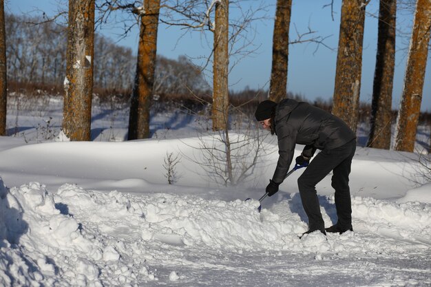 Mann entfernt Schnee mit Schaufel von der Straße im Wintertag