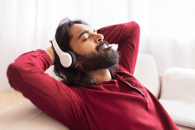 Mann entspannt sich zu Hause auf der Couch und hört Musik