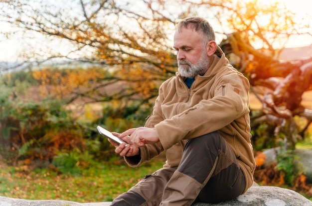 Mann erreicht Ziel, ruht sich aus und macht Fotos am Telefon im Peak District