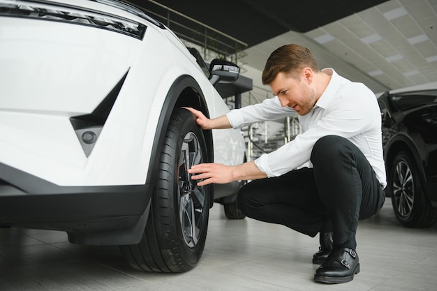 Mann erwachsener Kunde männlicher Käufer Kunde wählt Auto will neues Auto kaufen Touch Check Auto im Ausstellungsraum Fahrzeug Salon Autohaus Laden Motor Show Indoor Verkaufskonzept