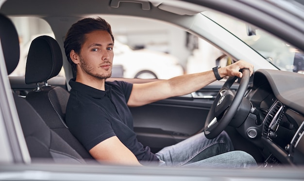 Mann fährt Auto im Autohaus