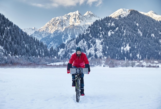 Mann fährt Fahrrad am zugefrorenen See