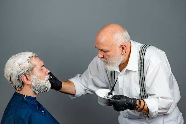 Mann färbt Haare im Friseursalon. Prozess einer Mannhaarfärbung im Friseursalon.