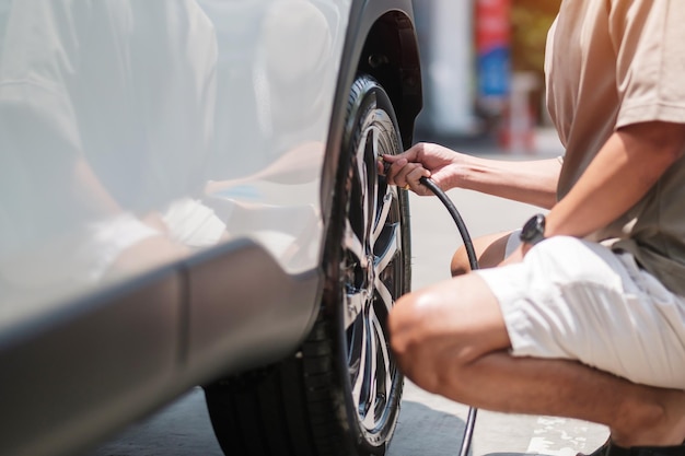 Mann Fahrer Hand Reifen des Fahrzeugs aufpumpen Reifenventil Stickstoffkappe zum Überprüfen des Luftdrucks und Füllen von Luft am Autorad an der Tankstelle Self-Service-Wartung und Sicherheit