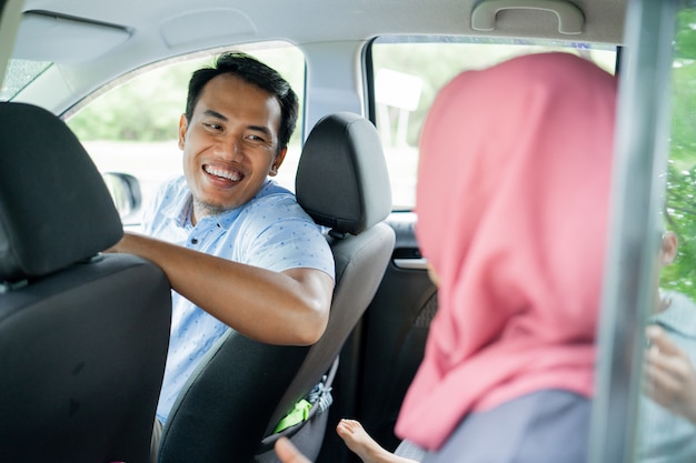 Mann Fahrer sieht lächelnd und glücklich aus, mit einem Hijab-Passagier zu plaudern