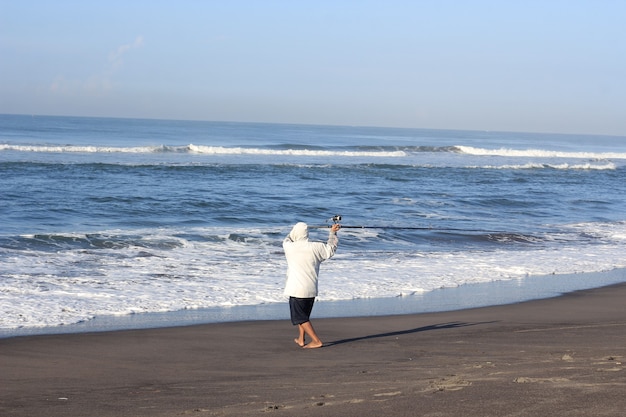 Mann fischt im Meer vom Strand aus
