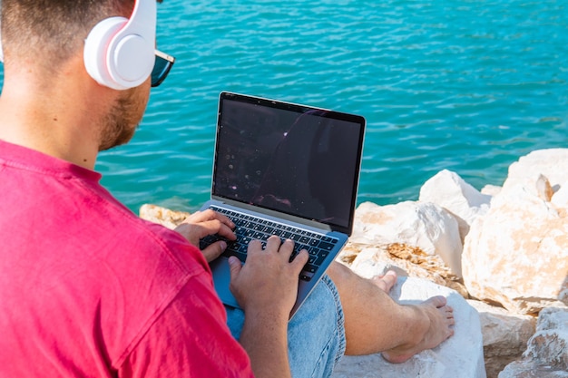 Mann-Freiberufler, der im Sommer an der Stadthafenbank am Laptop arbeitet