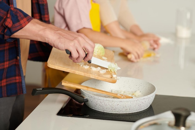 Mann fügt Zwiebel in heißen Topf hinzu