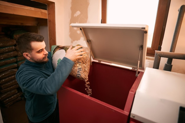 Mann füllt einen Pelletofen Heizraum mit Holzpellet-Heizofen Konzept einer nachhaltigen Haushaltsheizung der Zukunft