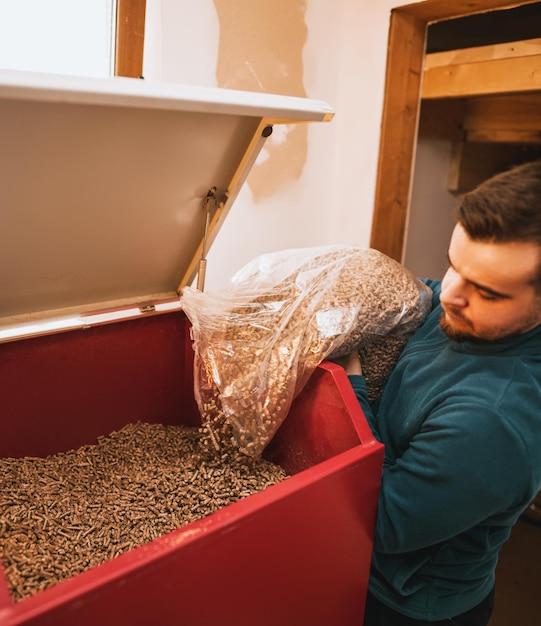 Mann füllt einen Pelletofen Heizraum mit Holzpellet-Heizofen Konzept einer nachhaltigen Haushaltsheizung der Zukunft