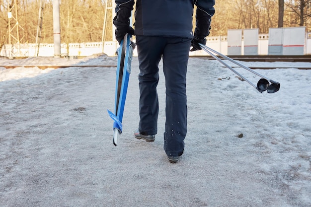 Mann geht Langlaufen in den Wald Person hat Skier und Stöcke in den Händen, er überquert die Eisenbahn