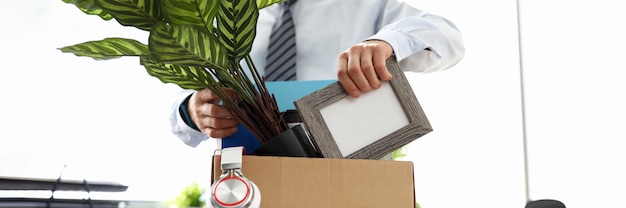 Mann Geschäftskleidung legt Dinge in Kiste im Büro