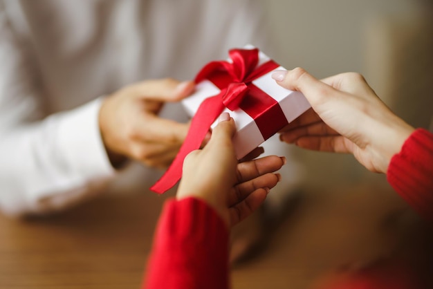 Mann gibt seiner Frau eine Geschenkbox mit rotem Band Hände des Mannes gibt Überraschungsgeschenkbox für Mädchen