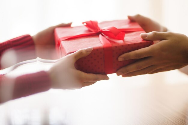 Mann gibt seiner Frau eine Geschenkbox mit rotem Band Hände des Mannes gibt Überraschungsgeschenkbox für Mädchen