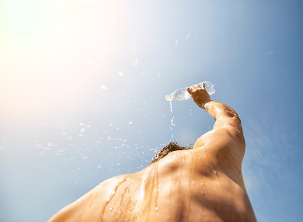 Mann gießt an heißen Tagen Wasser aus einer Plastikflasche auf den Kopf