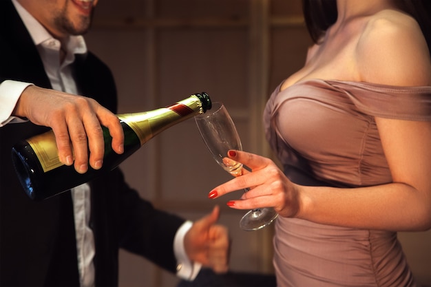 Mann gießt Champagner in ein Glas für seine Freundin. Urlaubs- und Feierkonzept