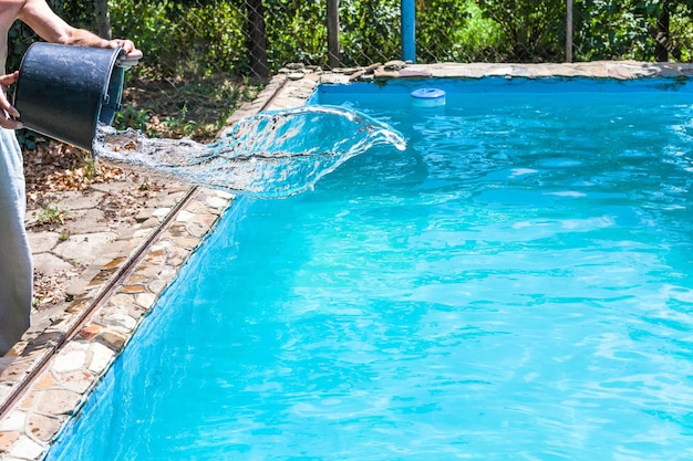 Mann gießt Desinfektionsmittel aus Eimer in den Pool