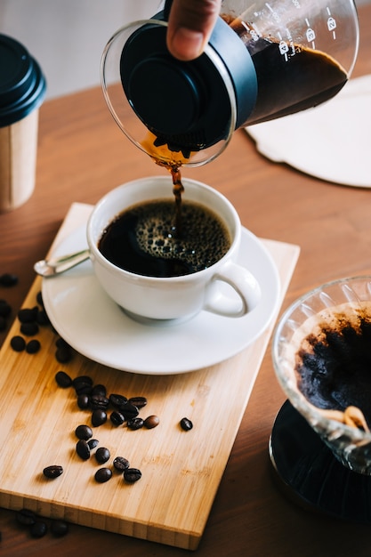 Mann gießt Kaffee in eine Tasse, alternative Kaffeebrühmethode, mit Gießen über Tropfer und Papierfilter.