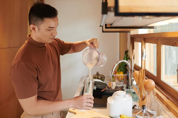 Mann gießt Milchshake in Flasche