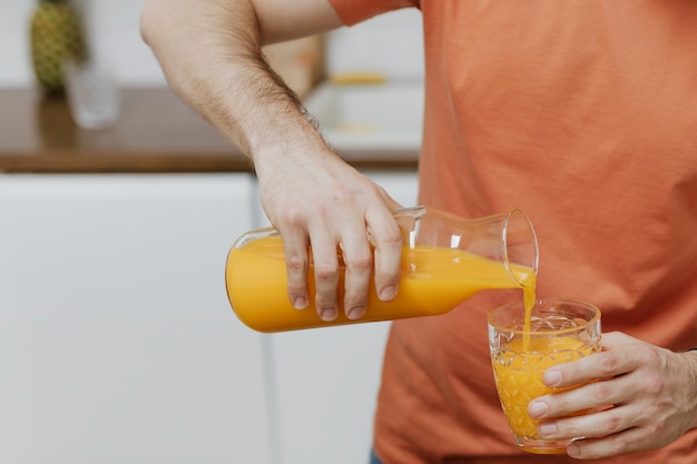 Mann gießt Orangensaft in ein Glas