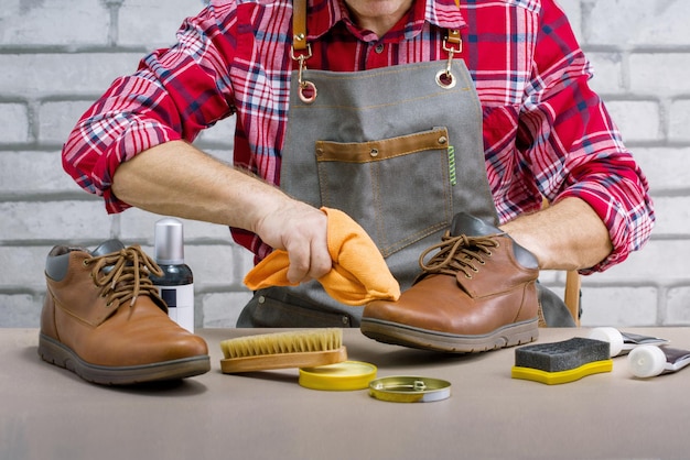Mann glänzende Schuhe mit einem Lappen in der Werkstatt. Konzept für kleine Unternehmen. Hausaufgaben.