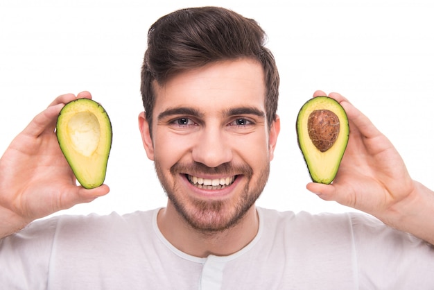 Mann hält Avocado und lächelt.