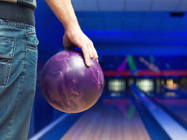 Mann hält Ball gegen Bowlingbahn