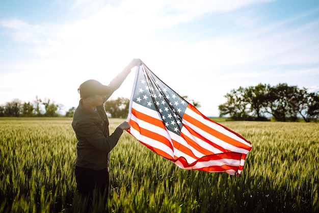 Mann hält die amerikanische USA-Flagge, Patriot hebt die nationale amerikanische Flagge, Unabhängigkeitstag, 4. Juli