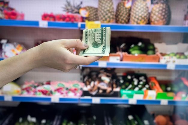 Mann hält Dollar im Supermarkt. Kaufkonzept