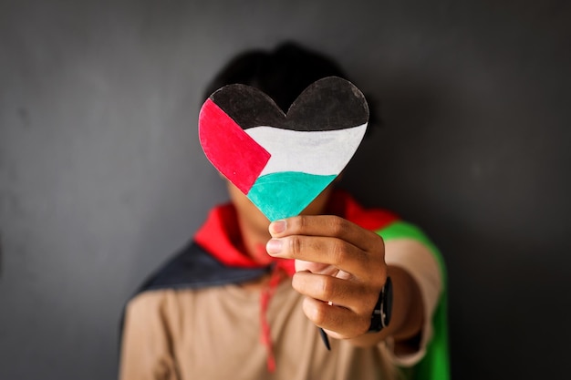 Foto mann hält ein herzförmiges papier mit den farben der palästinensischen flagge, um unterstützung und solidarität zu zeigen