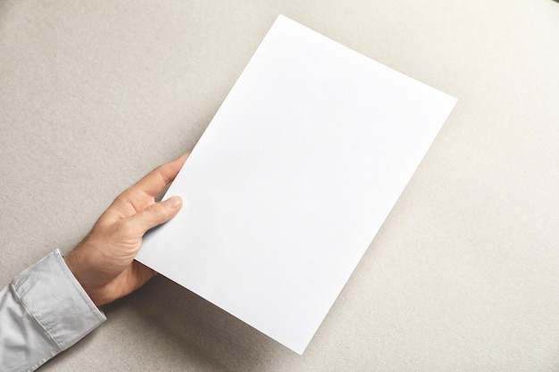 Mann hält ein leeres Blatt Papier auf hellem Hintergrund